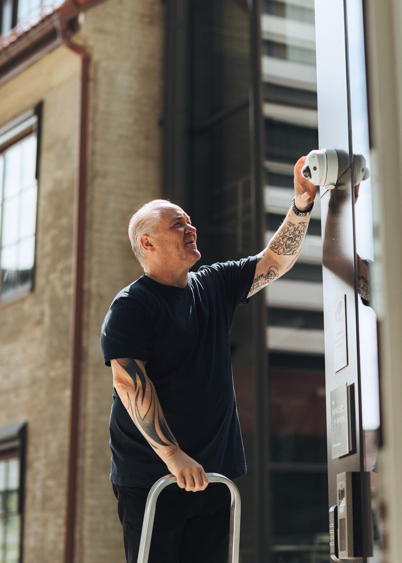 Mann på stige reparerer kamera