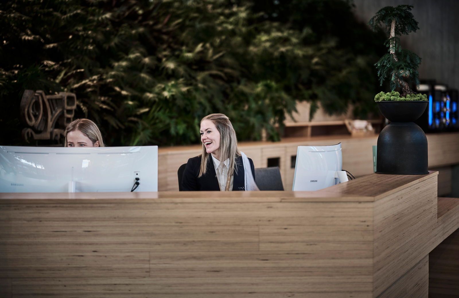 Resepsjonister bak resepsjonsbenk.