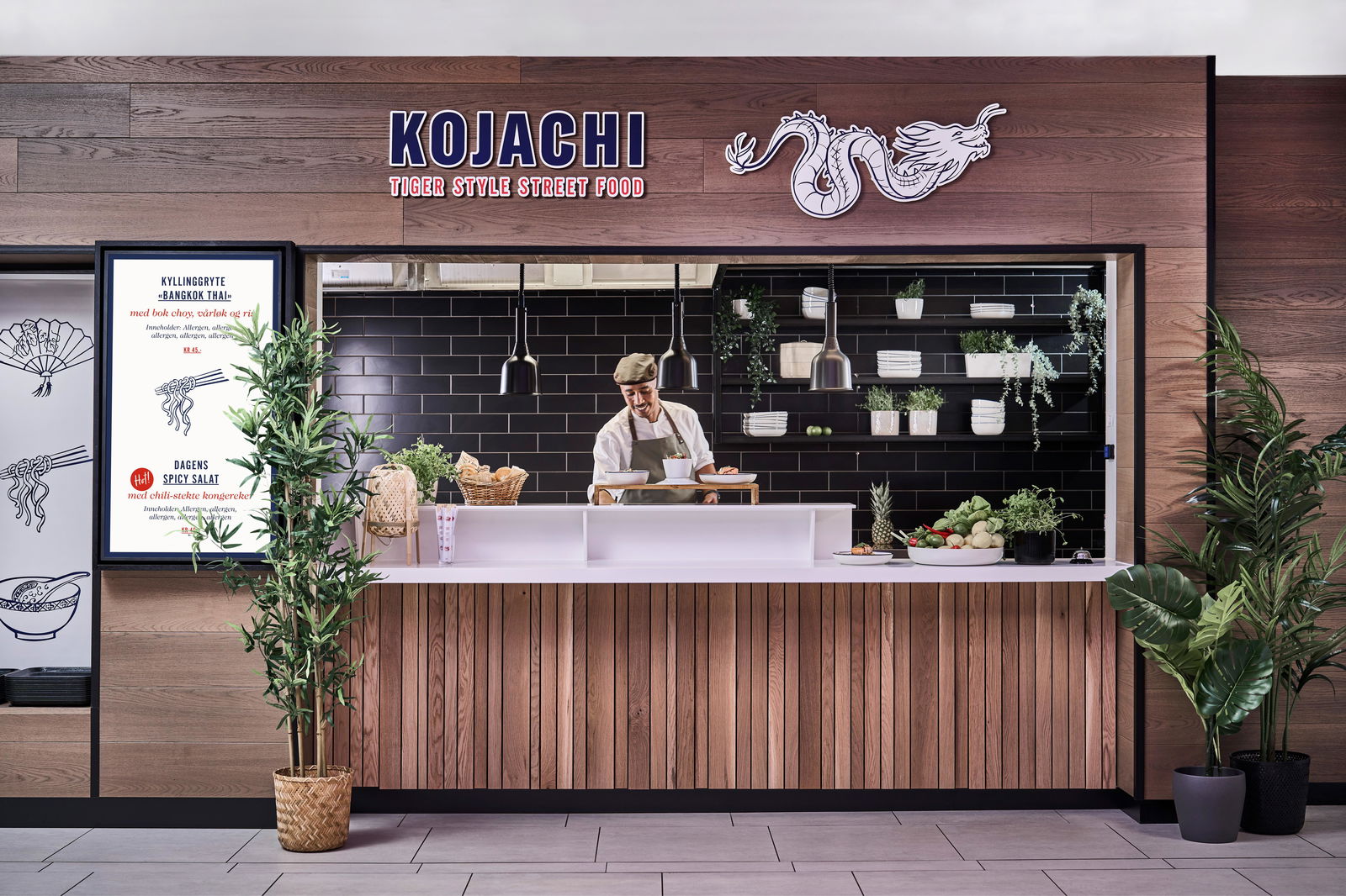 Mannlig kokk legger opp retter i Kojachi matbod i Food Court